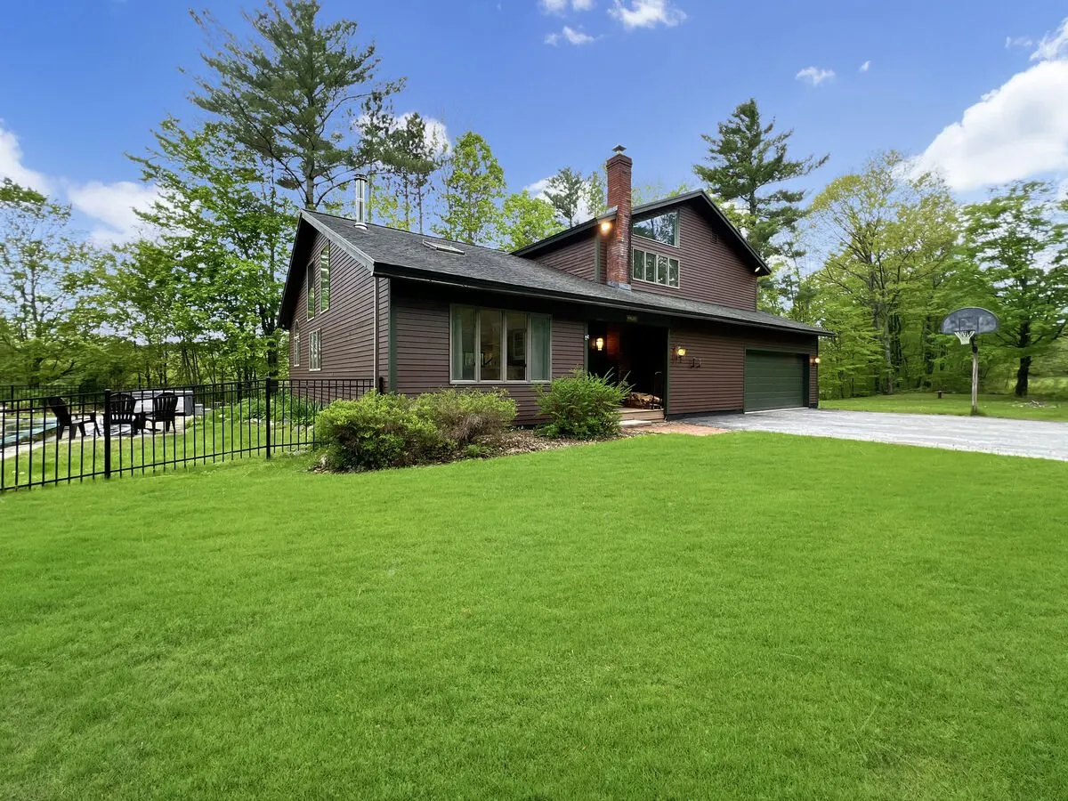 An exterior view featuring the house’s inviting facade, a manicured lawn, and a basketball hoop. The open green space is framed by trees, and the area looks ideal for family games, pets, and outdoor gatherings.