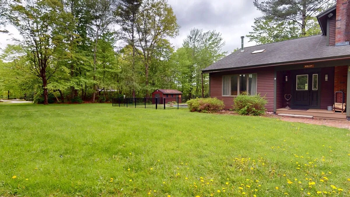 This exterior view highlights the home’s surrounding grassy lawn, mature trees, and a small shed—perfect for outdoor games, picnics, and relaxing in nature. The peaceful setting reinforces the idea of family and group enjoyment in a private, natural environment.