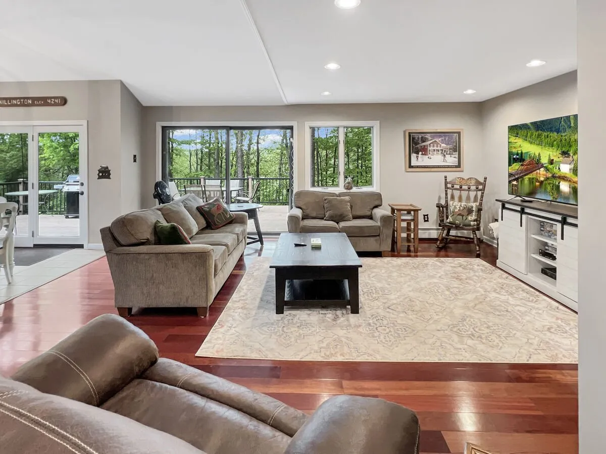 A cozy living room with plush sofas grouped around a coffee table, a large window framing the outdoors, and decorative art adding character. The room exudes comfort, perfect for movie nights, conversations, or enjoying the natural light.